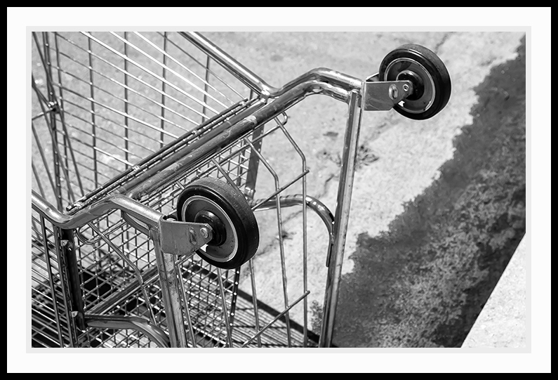 A shopping cart is seen lying in the gutter.